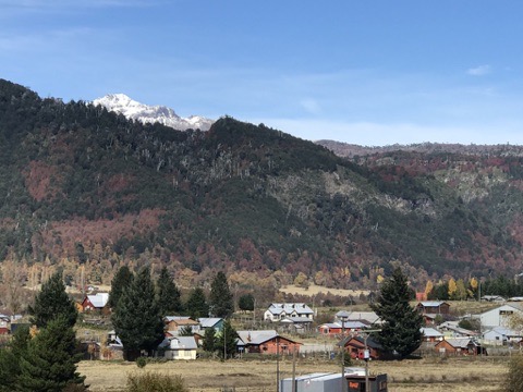 Vista del pueblo de Malalcahuello con casas, montañas y volcán nevado al fondo, mostrando la comunidad en su entorno natural